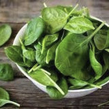 Bowl of Heirloom Organic Whale Spinach leaves on a wooden surface