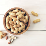 Wooden bowl filled with Heirloom Organic Raw Spanish Peanuts on a light wooden surface
