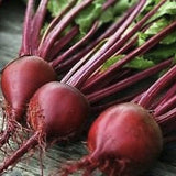 Heirloom Organic Ruby Queen with green tops on a wooden surface