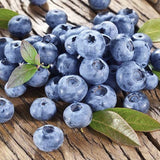 Blueberries with green leaves on a wooden surface