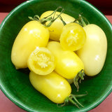 Green bowl filled with Rare Heirloom Organic Cream Sausage Tomato on a red surface