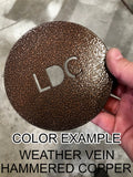 Round color sample with 'LDC' branding held by a hand on a concrete floor.