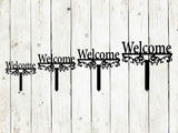 Decorative 'Welcome' sign with floral designs on a wooden background