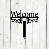 Decorative 'Welcome' sign with floral designs on a wooden background