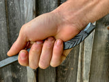 Hand holding a Dragon Fire Poker against a wooden background
