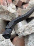 Black metal Dragon Fire Poker with a unique design on a rocky surface