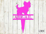 Pink dog-shaped sign with 'Abigail' on a wooden background