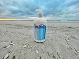 Bottle of Sea Salt body lotion on a sandy beach with ocean in the background