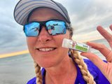 Person holding a small bottle labeled 'Coconut Milk' outdoors with a cloudy sky.