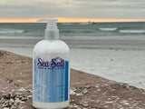 Sea Salt hand and body lotion bottle on a beach with ocean in the background