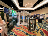 Exhibition hall with booths and people at a convention The Sago Greenhouse 5' x 8'