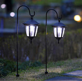Two solar-powered outdoor lamps on grass with a blurred background