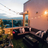 Outdoor patio with a sectional sofa, coffee table, and string lights overlooking a cityscape.