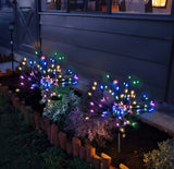 Colorful outdoor string lights shaped like fireworks in a garden setting.