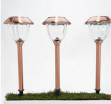 Three copper-colored solar garden lights on a white background