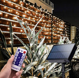 Solar string lights with remote control and panel on a wooden fence at night.