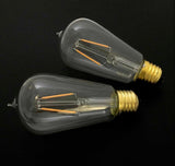 Two clear light bulbs with gold bases on a black background