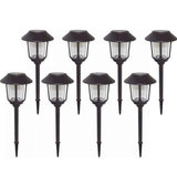 Set of eight black solar garden lights on a white background