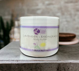 Jar of lavender lemongrass body butter on a concrete surface with a blurred background