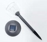 Solar-powered outdoor light with clear cover and solar panel on a white background