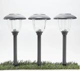 Three solar garden lights on grass with a white background