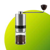 Handheld coffee grinder with a clear container of ground coffee on a green background