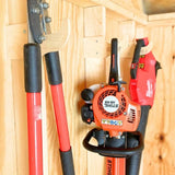 Gardening tools including a hedge trimmer and a chainsaw mounted on a wooden wall.