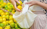 Person selecting lemons from a cloth bag amidst a lemon harvest.
