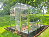 Janco Greenhouse in a garden with grass and trees in the background