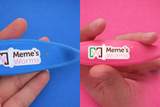 Two Worm Combs, one blue and one pink, held by hands with 'Meme's Worms' branding on a blue and pink background.