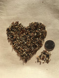 Heart-shaped pile of Pollinator Paradise Native Mix next to a quarter on a beige surface