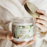 Person holding a jar of 'Revive' bath salts with a gold lid.