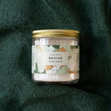 Jar of 'Revive' bath salts on a green textured background