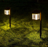 Two illuminated garden lanterns on grass at night