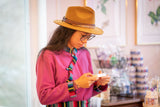 Woman wearing a yellow hat and pink jacket in a store setting