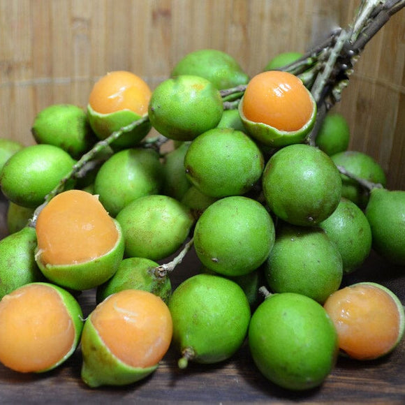 Mamoncillo fruits on a wooden surface with a wooden wall background