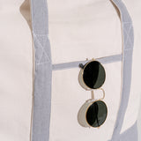 Round sunglasses with gold frame and black lenses on a light fabric background