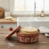 Ceramic tortilla warmer with tortillas on a wooden table in a kitchen setting