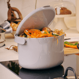 White kitchen compost bin filled with food scraps on a stove