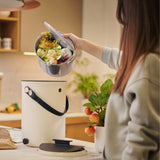 Person using a kitchen waste disposal unit with a salad in a bowl