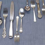 Silverware including forks, knives, and spoons on a blue fabric background