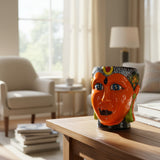 Decorative vase shaped like a face on a wooden table in a living room.