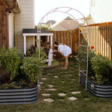 Woman and child in a garden with raised planters and a metal archway.