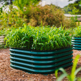 Green raised garden bed with plants in a garden setting