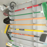 Set of gardening tools including shovels, rakes, and brooms hanging on a wall organizer.
