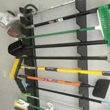 Set of gardening tools including shovels, rakes, and brooms on a wall-mounted rack.