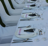Elegant table setting with white tablecloth, silverware, Fresh Culinary Lavender Bundles 14-18 inch Food Grade Dried Herbs, and wine glasses on a white chair background.
