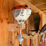 Stihl power tool mounted on a wooden wall with other tools in the background